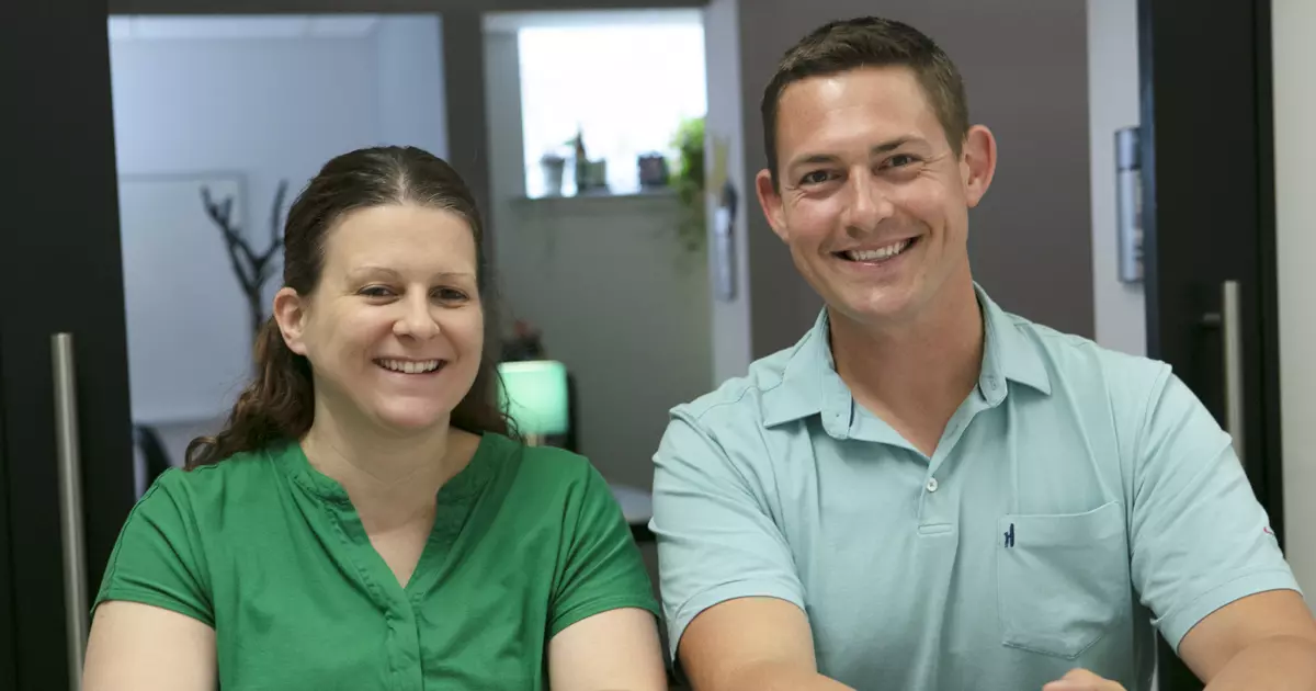 Two people in green shirts smiling