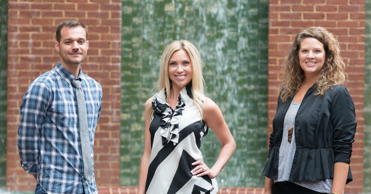 3 people standing in front of brick wall 