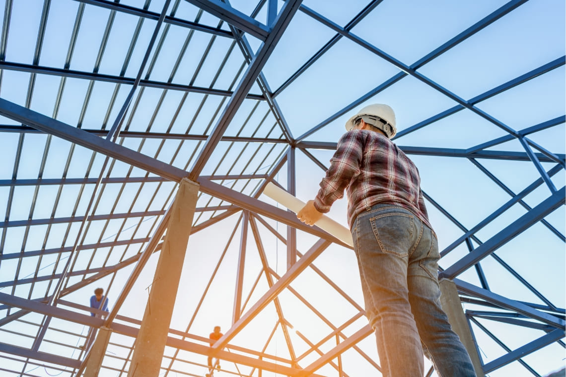 Construction worker holding blueprints on building site hero image