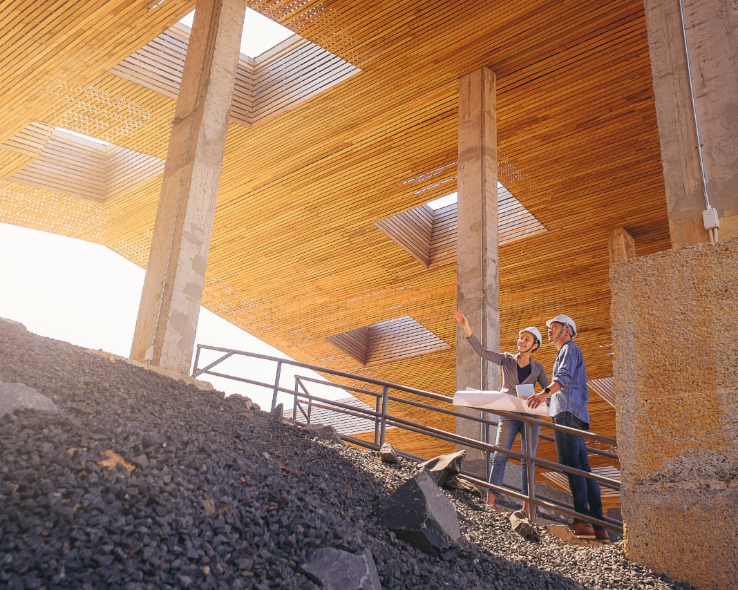 Two people looking at blueprints on a construction site