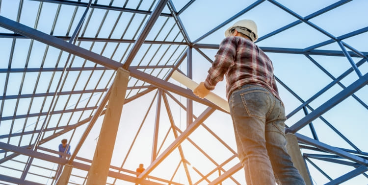Construction worker holding blueprints on building site grid image