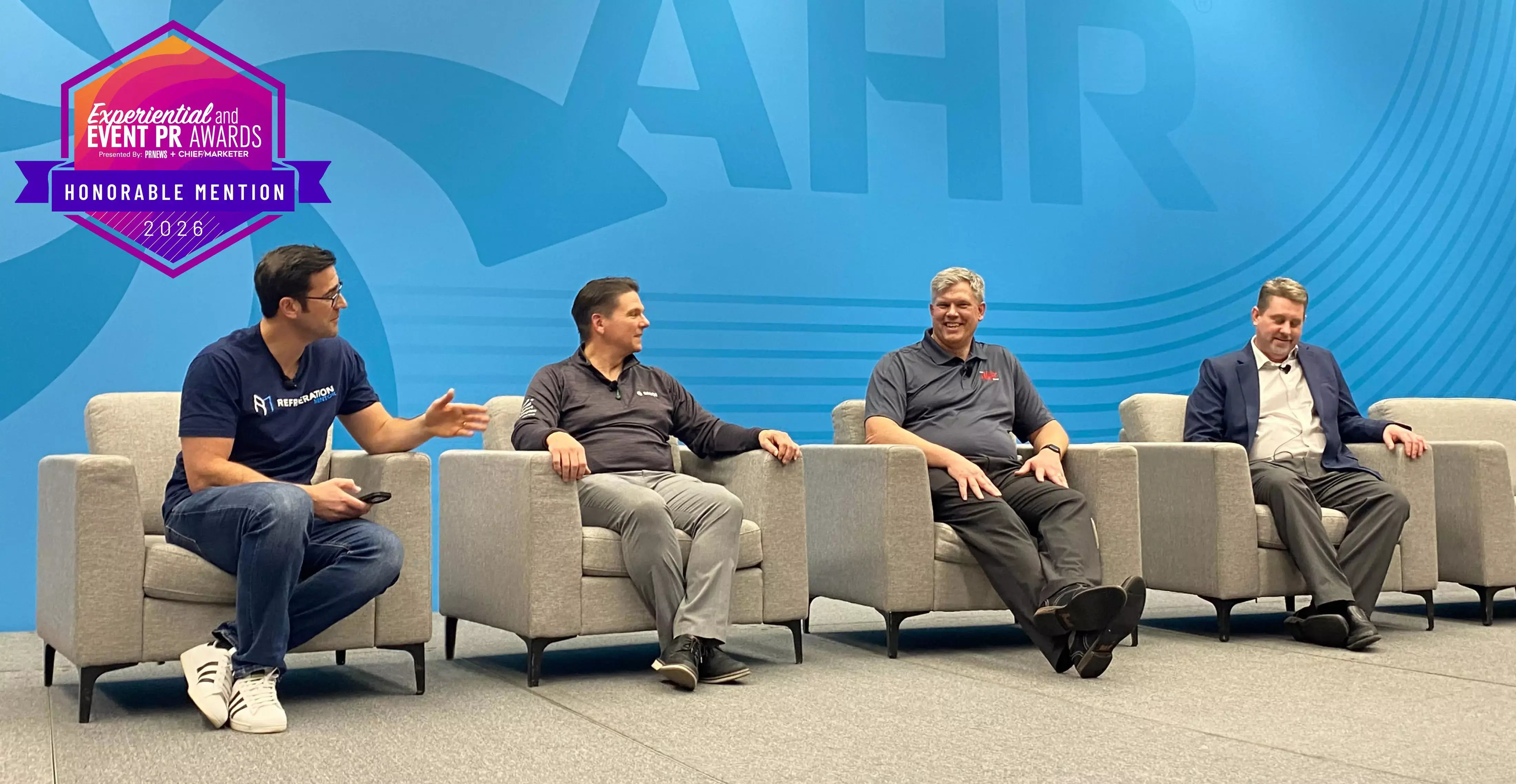 Four HVAC industry professionals sit in armchairs during an AHR Expo panel, with a 2026 Experiential and Event PR Awards Honorable Mention badge.