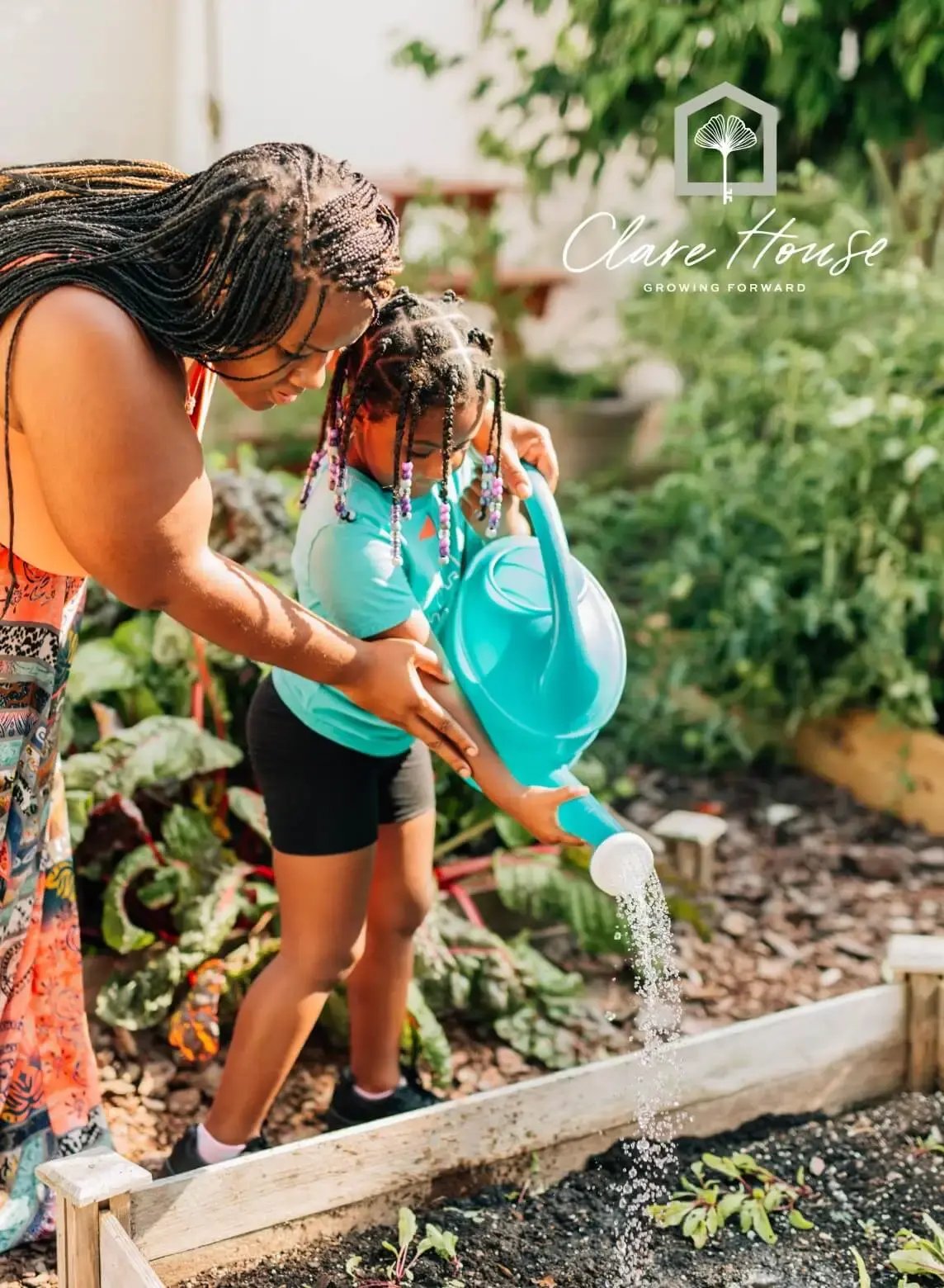 Mother and child water a raised garden bed together beneath the Clare House logo and Growing Forward tagline in a warm outdoor setting.