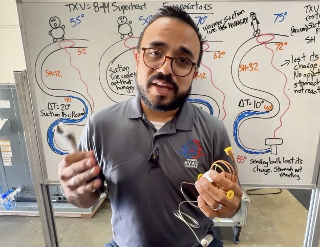 HVAC professional holds refrigeration components while explaining system operation in front of a technical whiteboard.