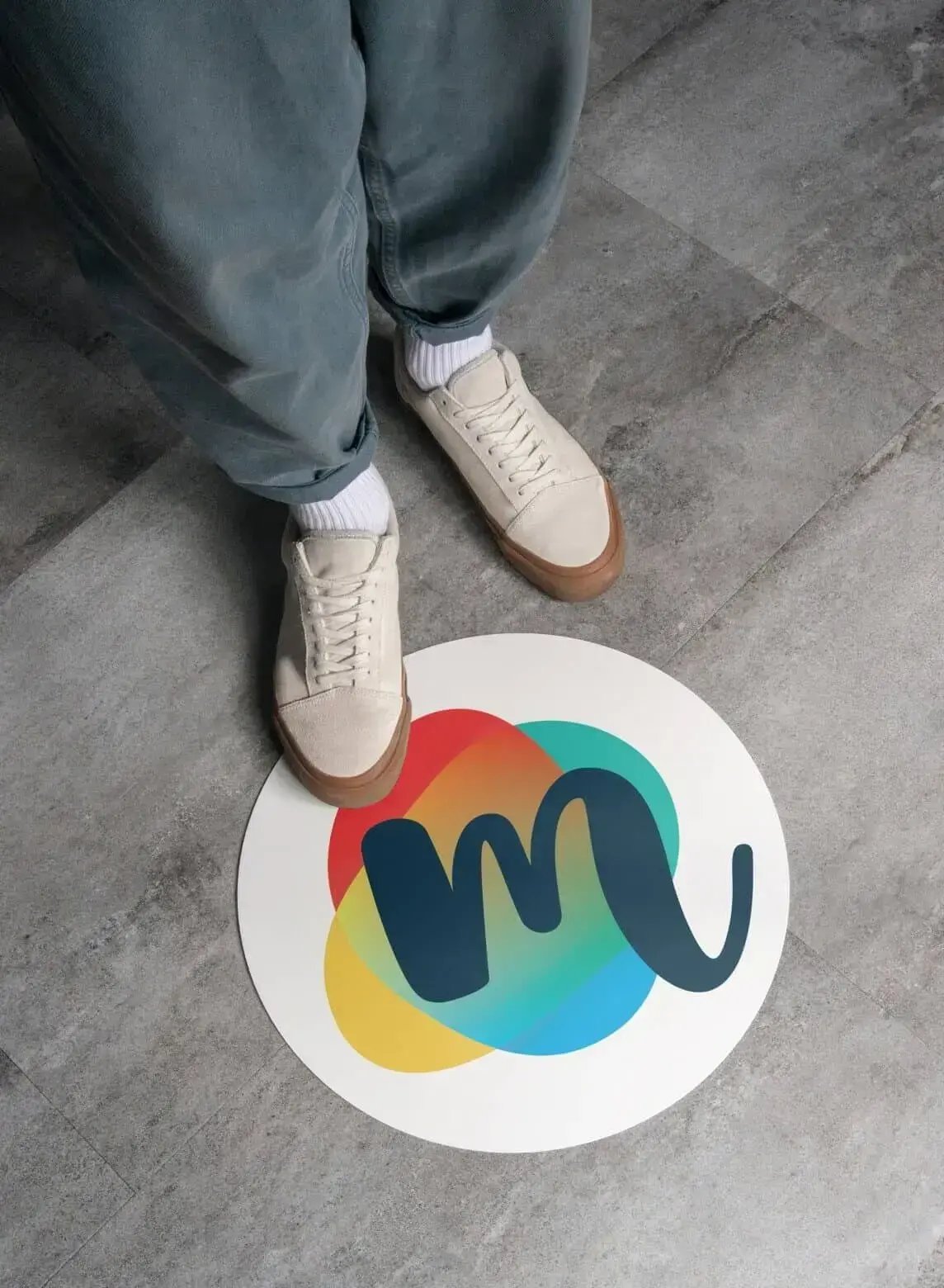 Person stands beside a floor graphic featuring The Mix colorful logo, showing how the refreshed brand identity extends into physical spaces.