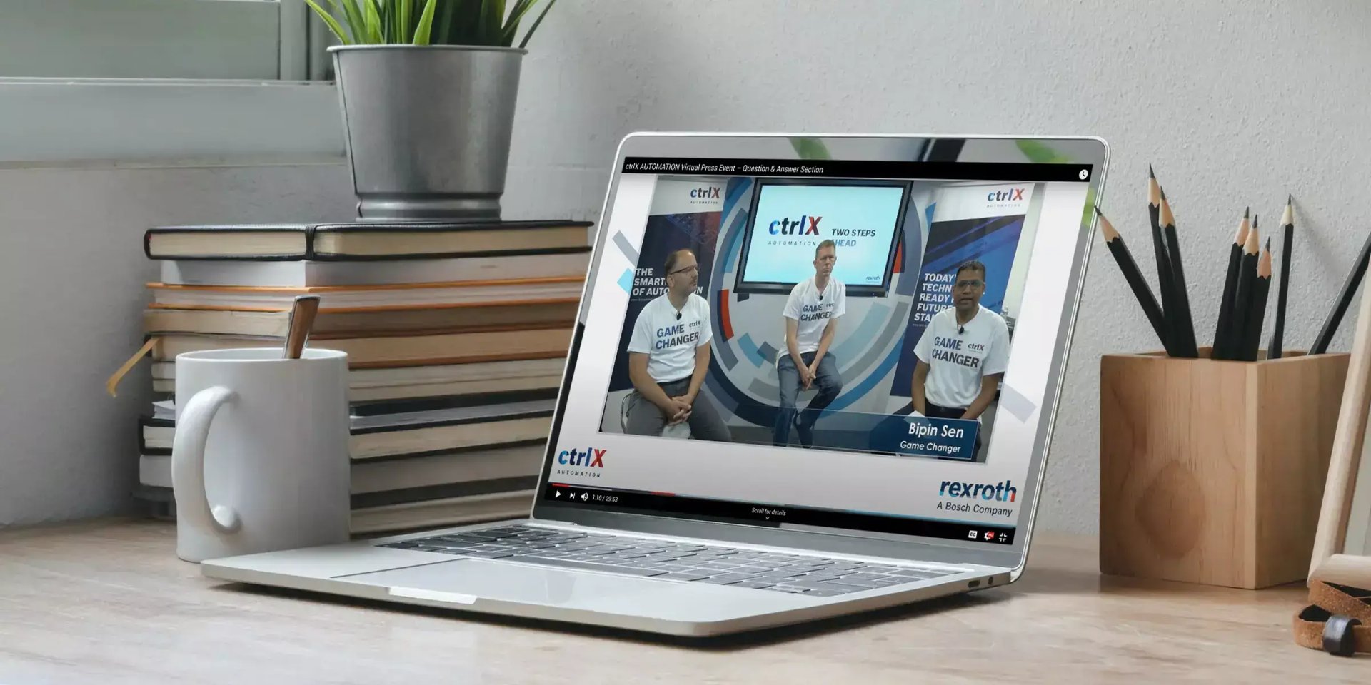 Laptop on a desk displays three Bosch Rexroth presenters during a virtual ctrlX Automation press event.