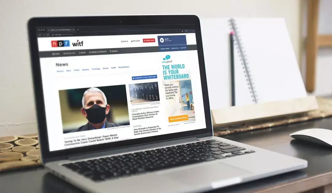 Laptop displays an NPR news page with an IdeaPaint ad promoting dry erase paint for homes and offices.