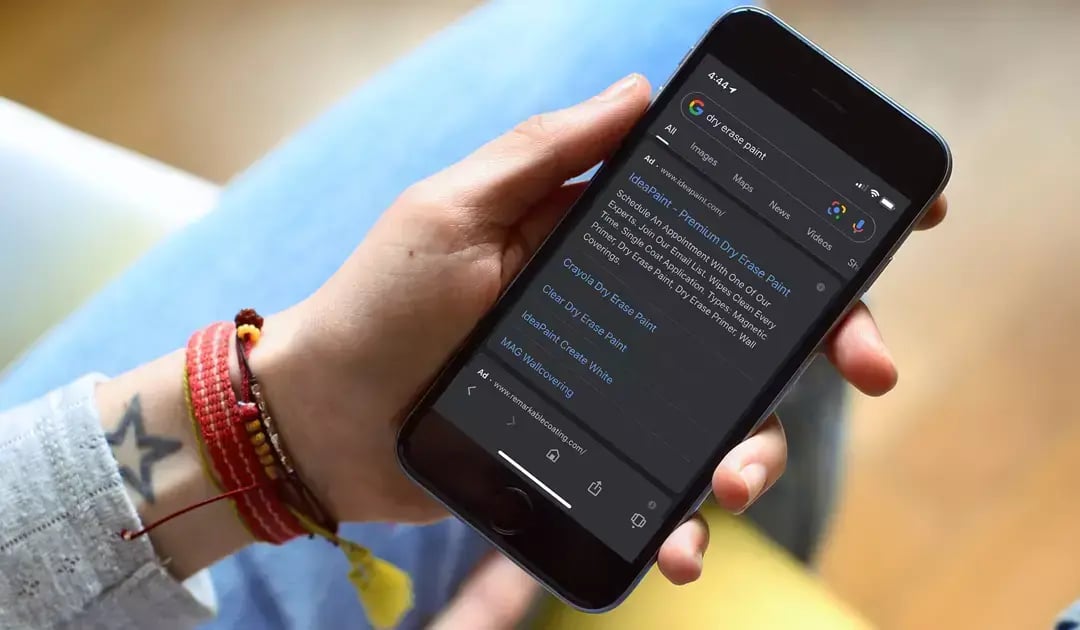Person holds a smartphone displaying Google search results and a sponsored ad for IdeaPaint dry erase paint.