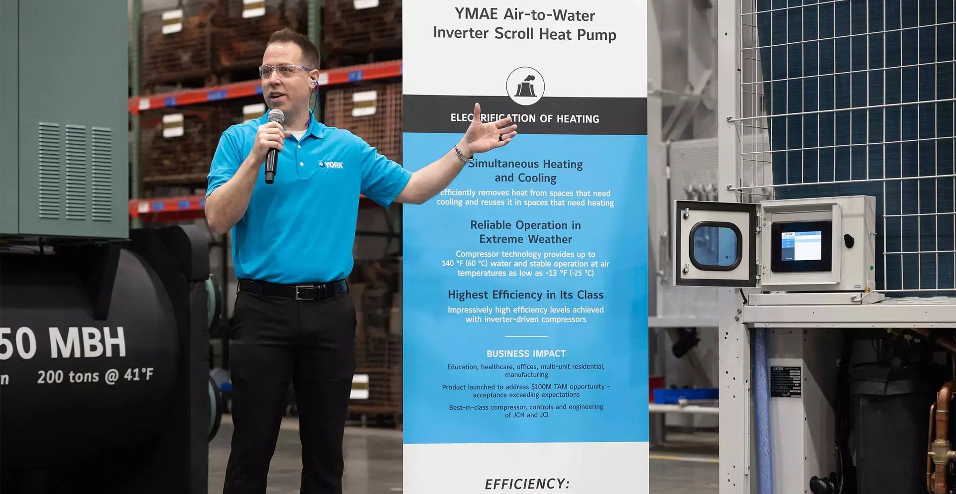 Johnson Controls employee presents beside a YORK heat pump display inside the JADEC engineering and testing facility during a VIP visit.