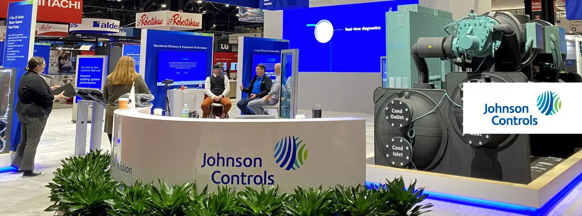 Johnson Controls booth at AHR Expo features a large YORK chiller display while attendees gather for interviews and product discussions.