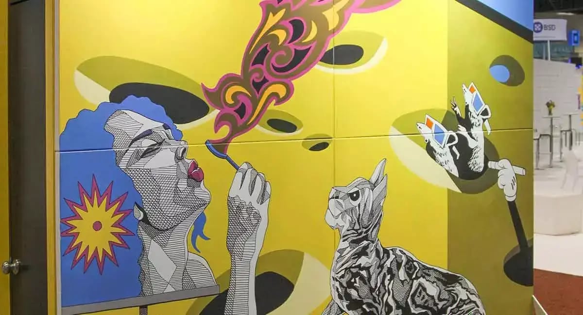 Colorful illustrated mural at the Sto trade show booth features a woman blowing bubbles alongside a cat and other playful graphics.
