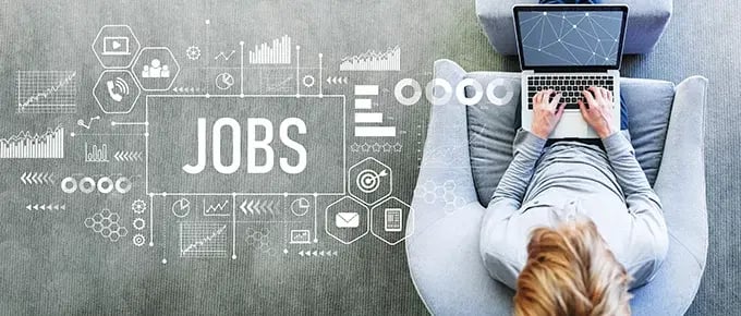 job-search-680Person uses a laptop beside a “JOBS” graphic surrounded by charts and digital icons, representing online job searching and career opportunities.
