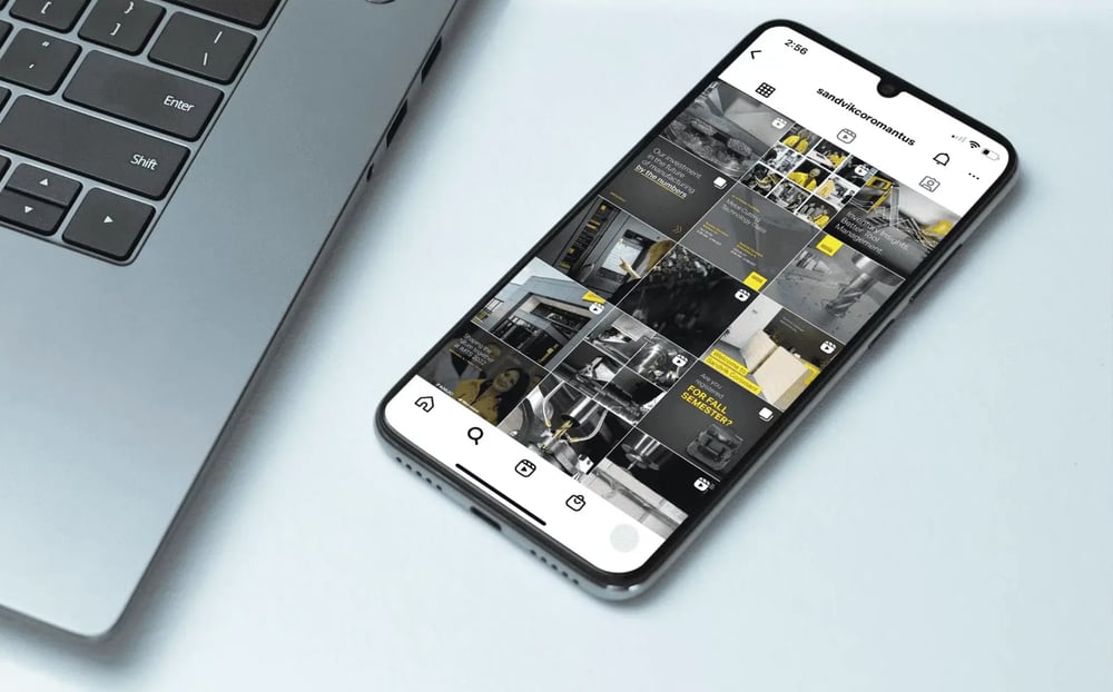 Smartphone beside a laptop displays Sandvik Coromant’s Instagram profile, featuring a grid of branded industrial manufacturing posts.