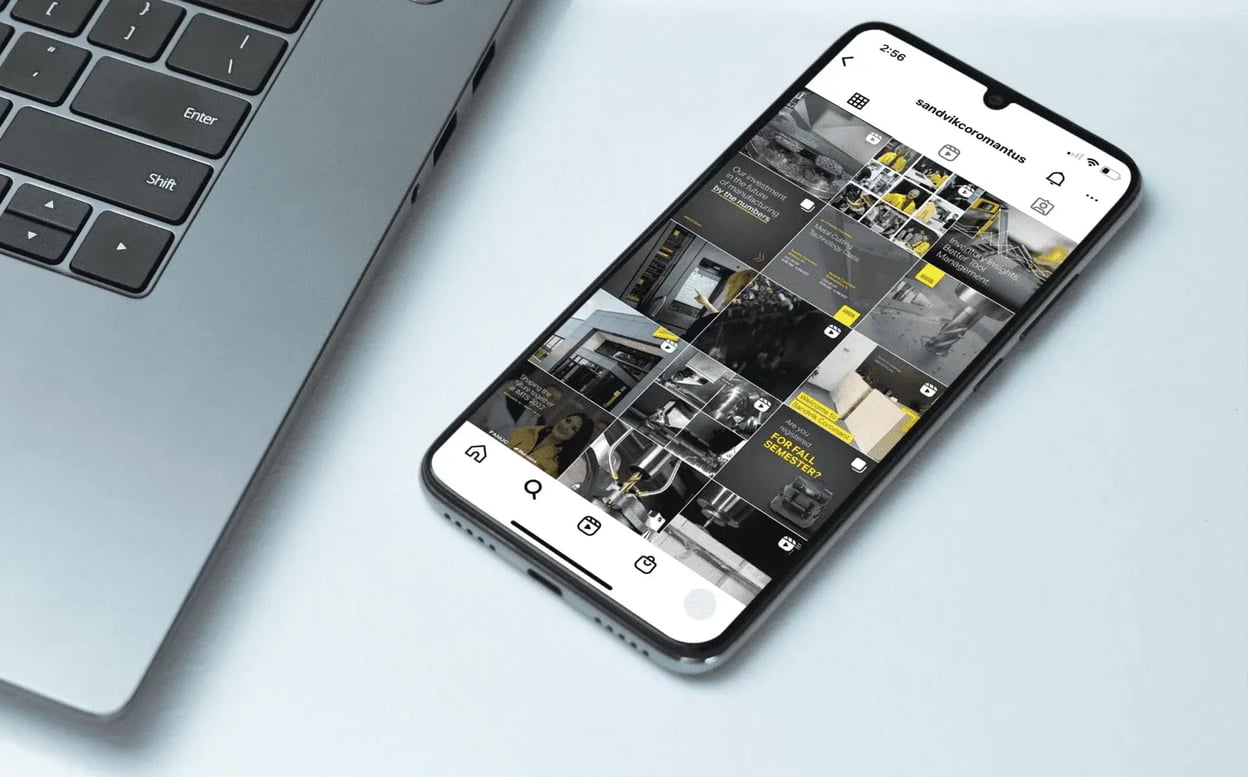 Smartphone beside a laptop displays Sandvik Coromant’s Instagram profile, featuring a grid of branded industrial manufacturing posts.